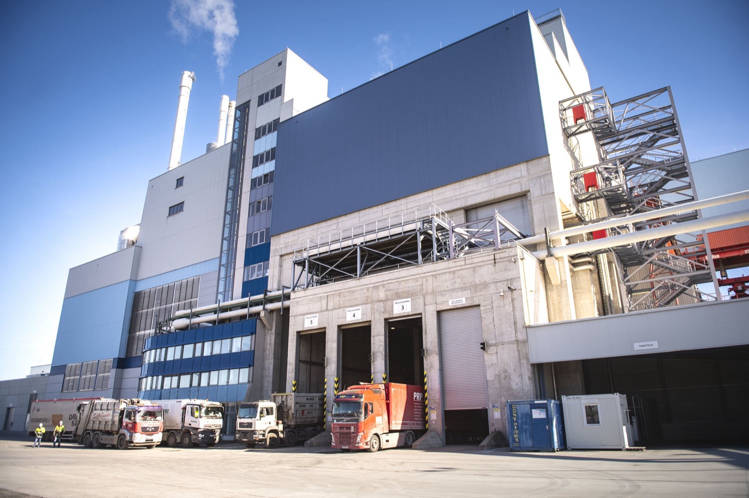 EVN plant with trucks at the unloading bays and steam rising from the stacks.